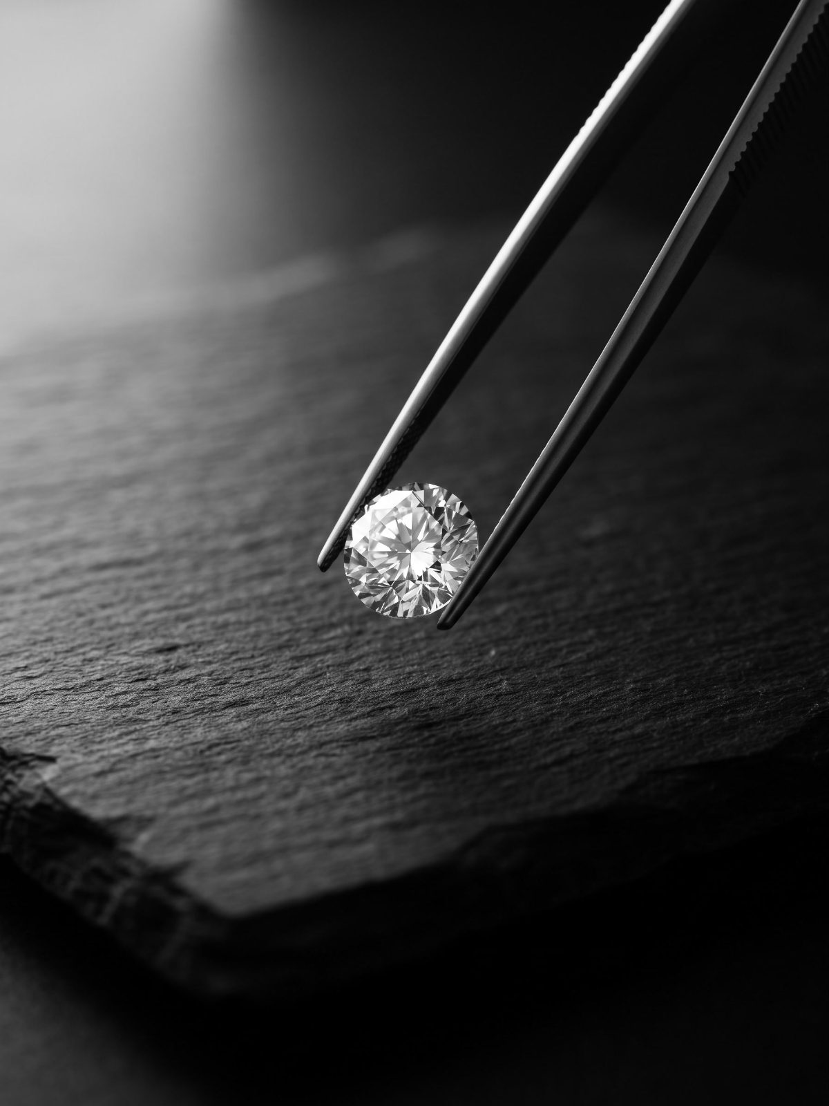 Loose round brilliant diamond in steel tweezers