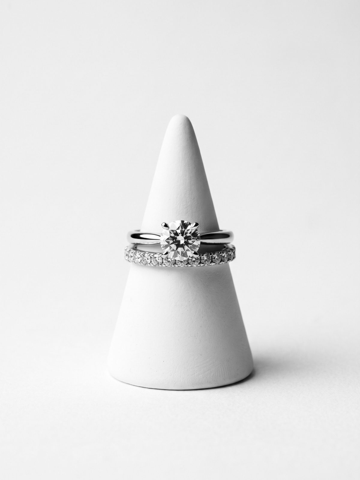 Diamond pavé wedding ring stacked beneath a solitaire engagement ring